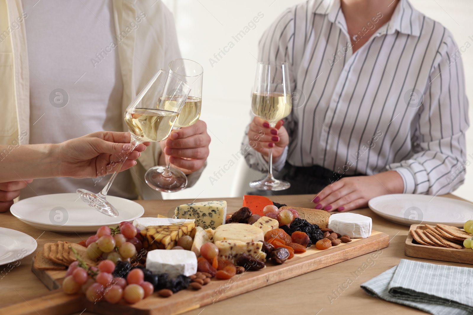 Photo of People clinking glasses of wine at served table, closeup