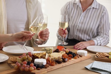 Photo of People clinking glasses of wine at served table, closeup