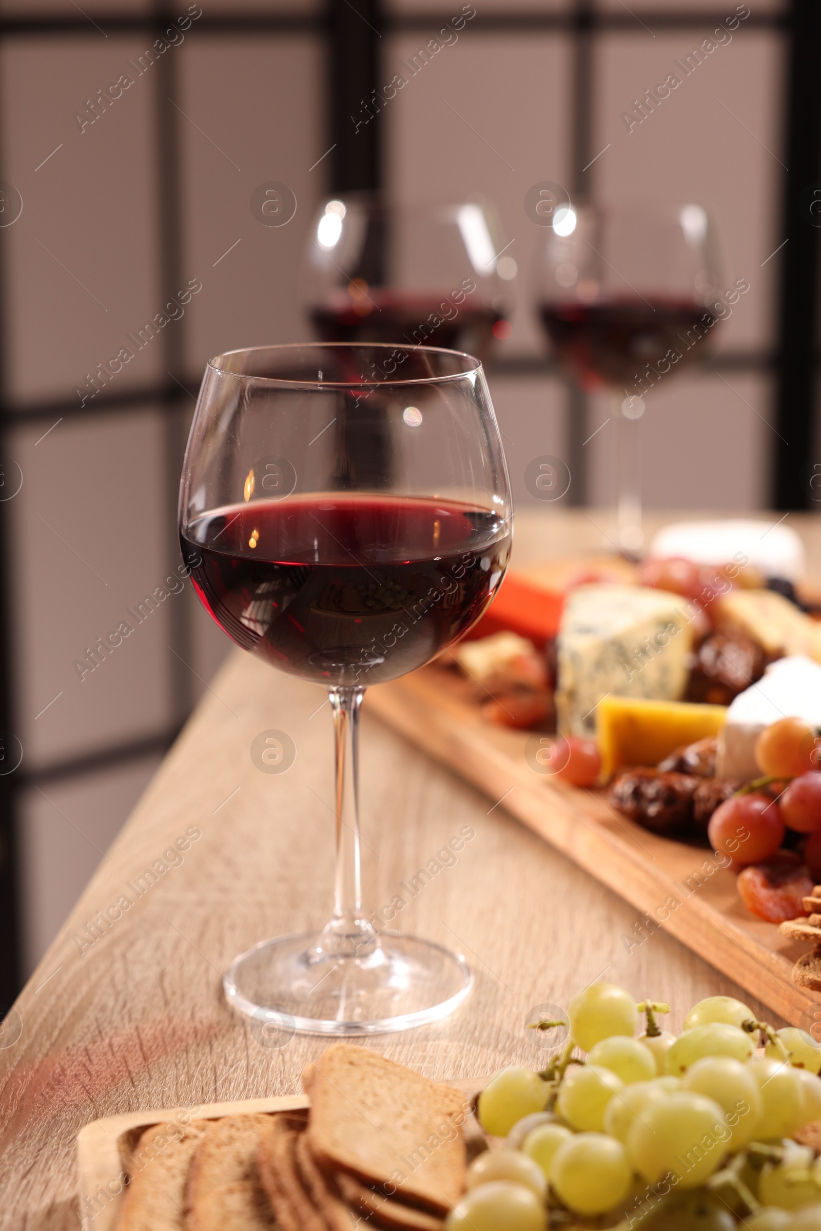 Photo of Glasses of red wine and different snacks on wooden table