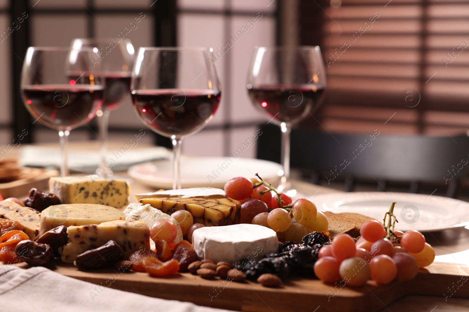 Photo of Glasses of red wine and different snacks on table, selective focus