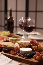 Photo of Glasses of red wine and different snacks on table, selective focus