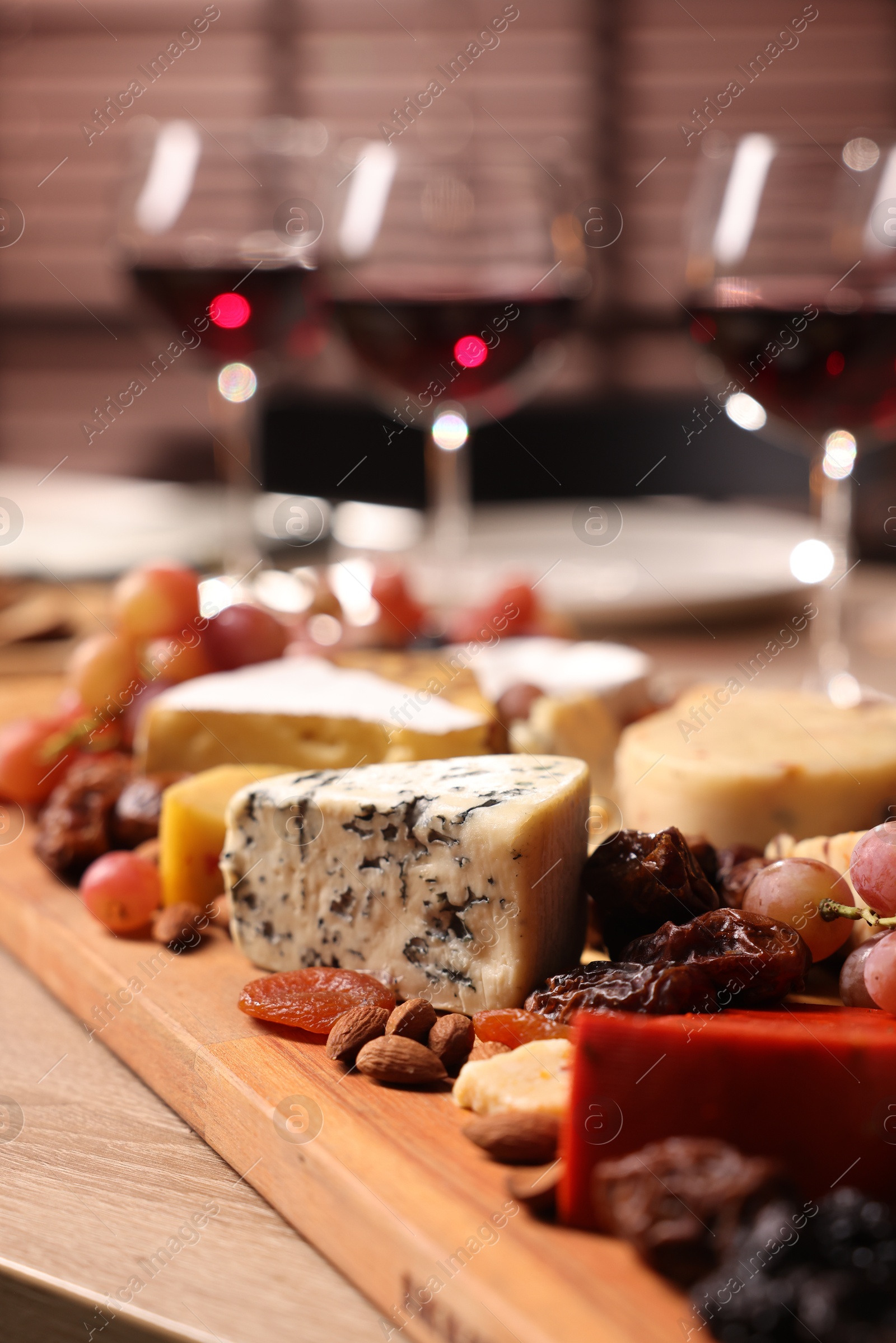 Photo of Glasses of red wine and different snacks on wooden table, selective focus