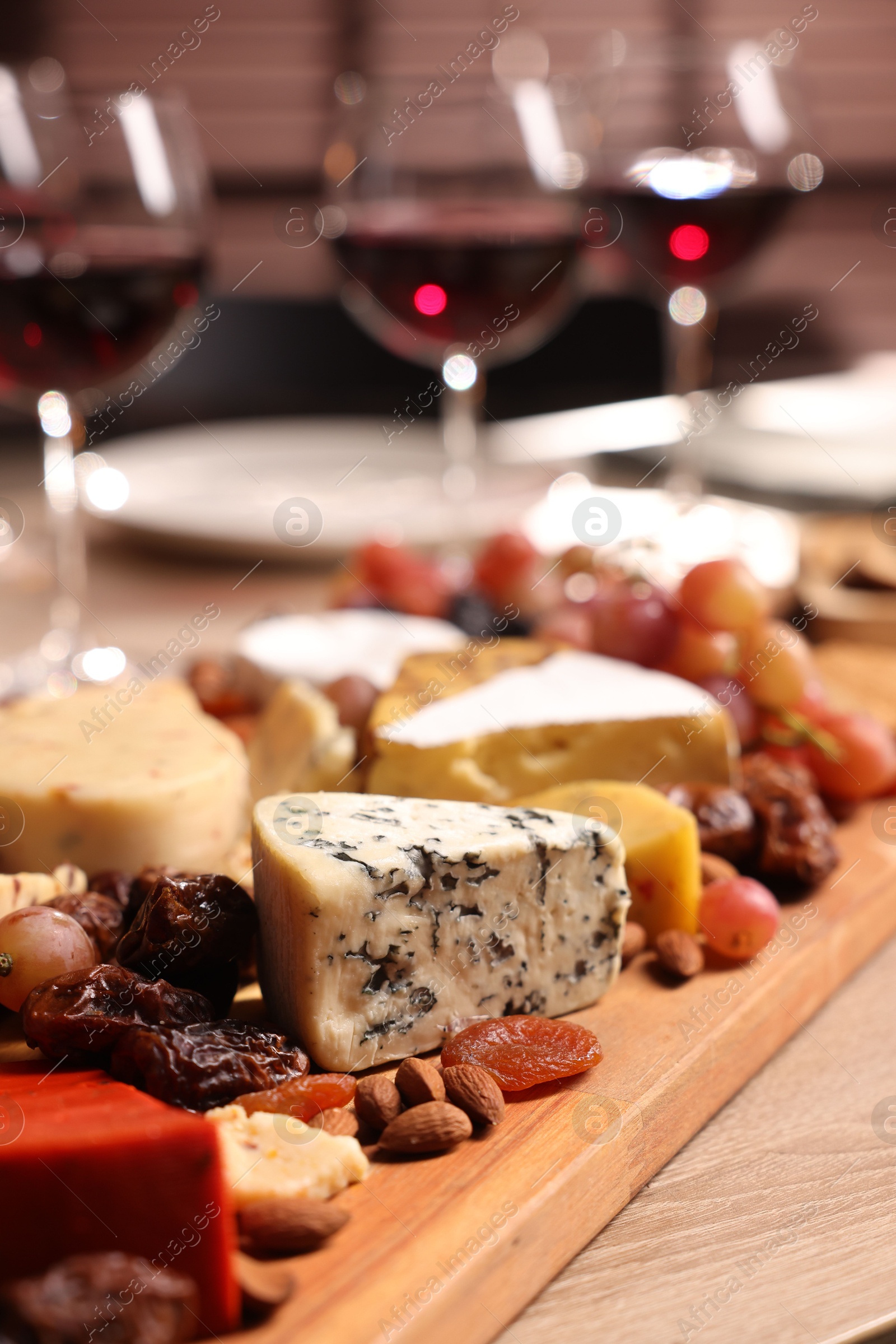 Photo of Glasses of red wine and different snacks on wooden table, selective focus