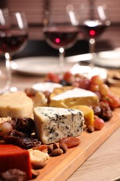 Glasses of red wine and different snacks on wooden table, selective focus