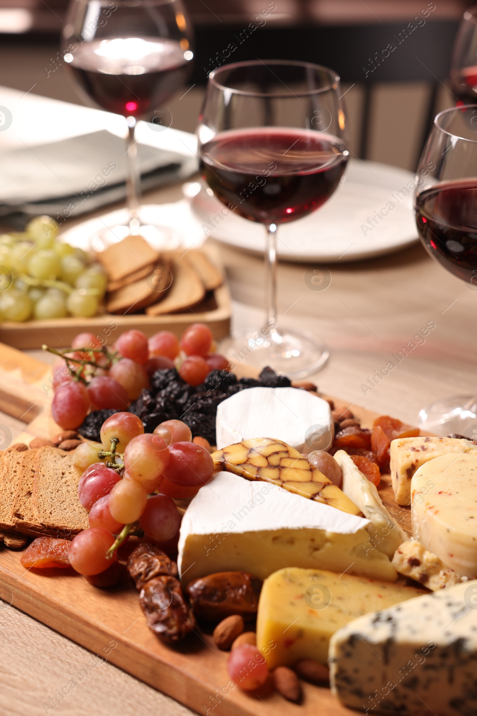 Photo of Glasses of red wine and different snacks on wooden table, selective focus