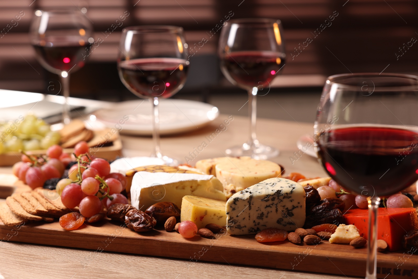 Photo of Glasses of red wine and different snacks on wooden table, selective focus