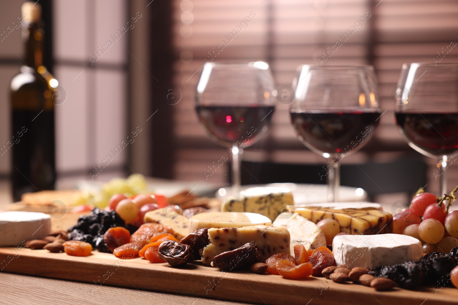 Photo of Glasses of red wine and different snacks on wooden table, selective focus