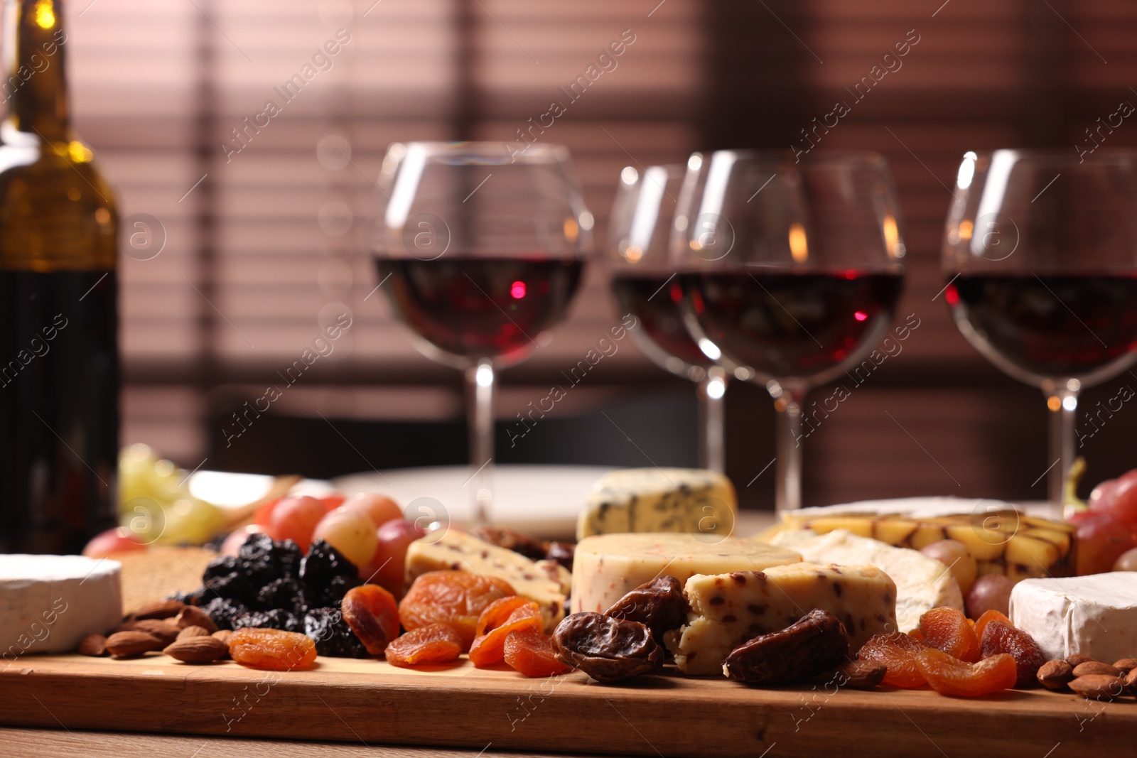 Photo of Glasses of red wine and different snacks on table, selective focus