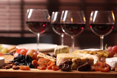 Photo of Glasses of red wine and different snacks on table, selective focus