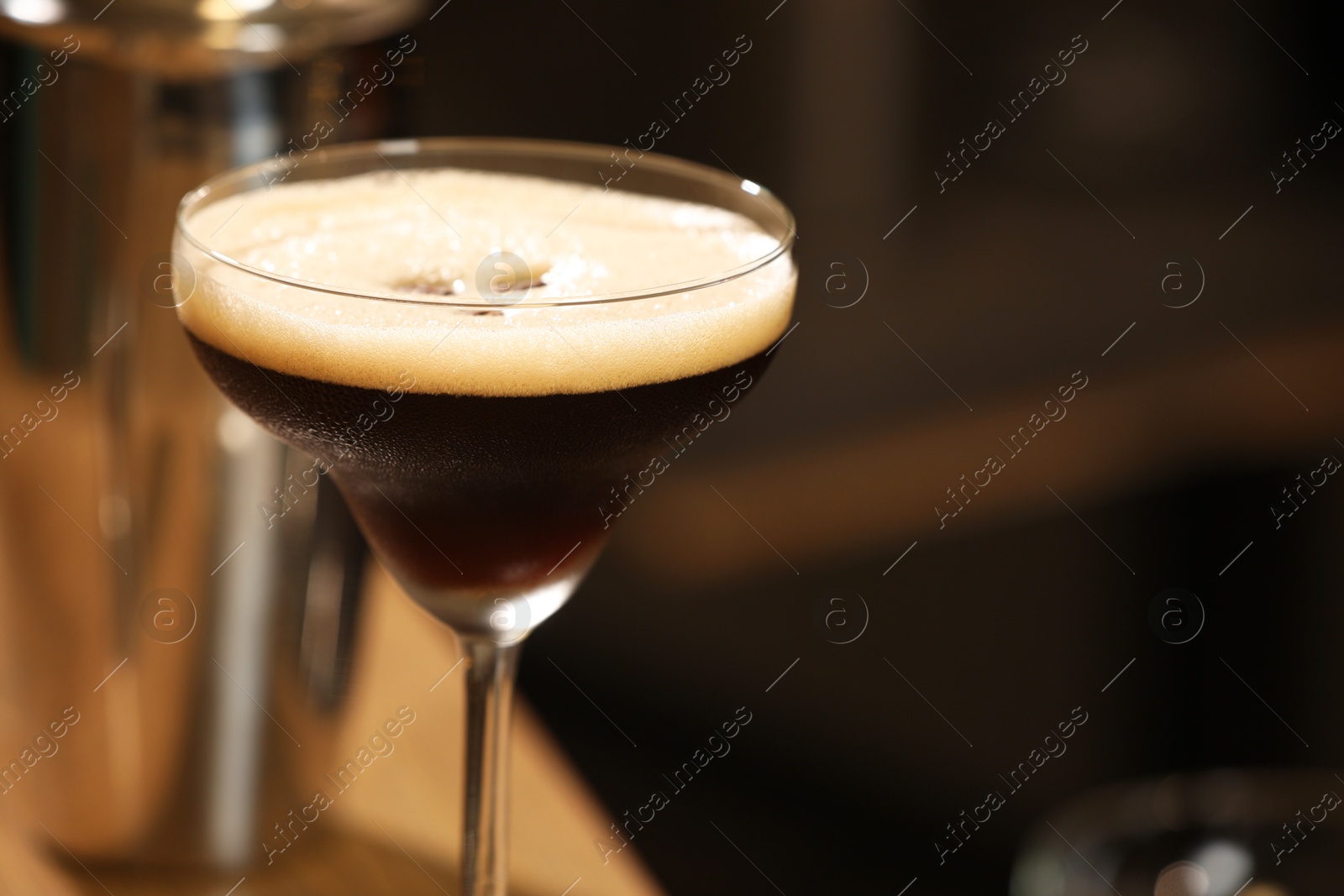 Photo of Delicious espresso martini in glass on blurred background, closeup. Space for text