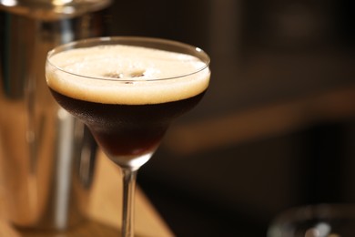 Delicious espresso martini in glass on blurred background, closeup. Space for text