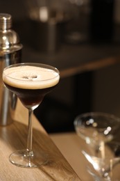 Glass with delicious espresso martini on wooden table in bar