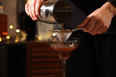 Bartender making delicious espresso martini in bar, closeup