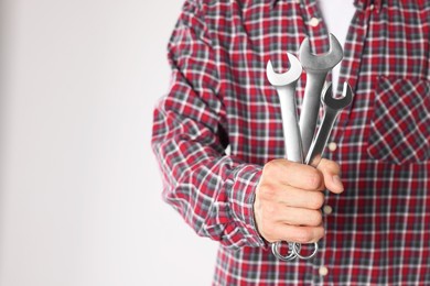 Photo of Auto mechanic with wrenches on light grey background, closeup. Space for text