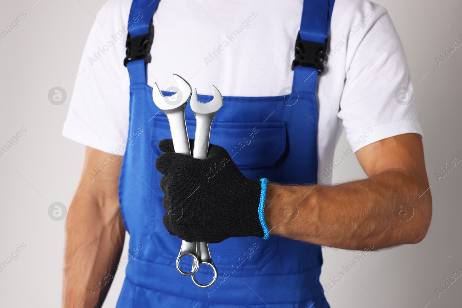 Photo of Auto mechanic with wrenches on light grey background, closeup