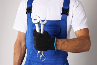 Photo of Auto mechanic with wrenches on light grey background, closeup