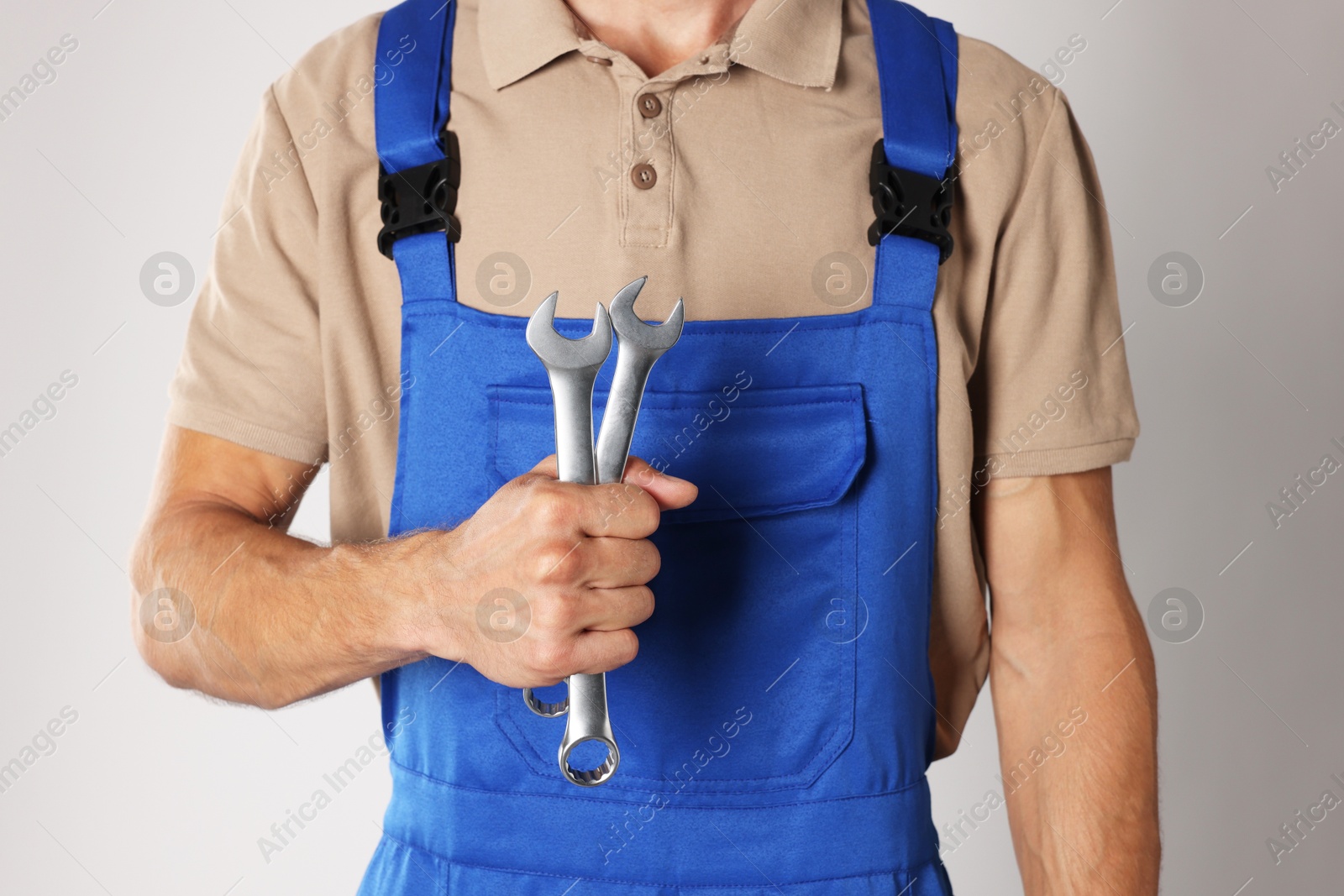 Photo of Auto mechanic with wrenches on light grey background, closeup