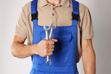 Photo of Auto mechanic with wrenches on light grey background, closeup