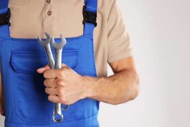 Photo of Auto mechanic with wrenches on light grey background, closeup