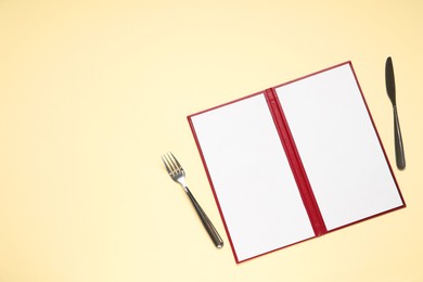 Photo of Hardcover notebook with blank sheets for menu design and cutlery on beige table, flat lay. Space for text