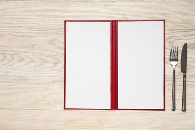 Photo of Hardcover notebook with blank sheets for menu design and cutlery on wooden table, flat lay