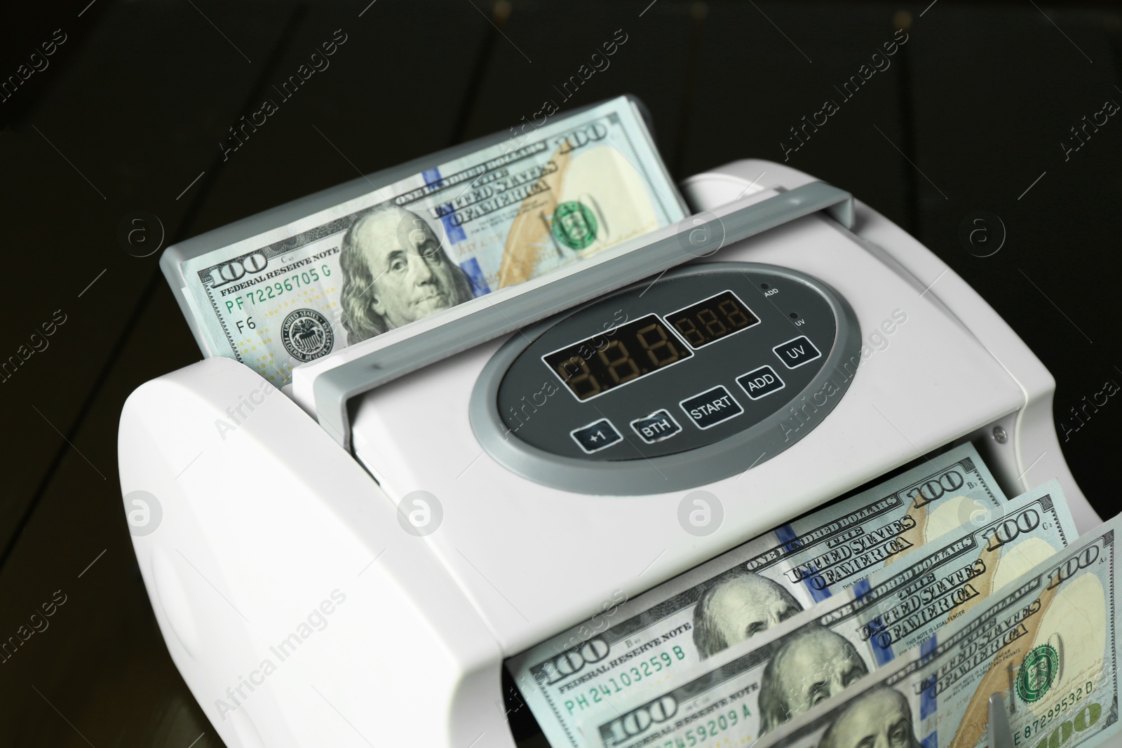 Photo of Money counter machine with dollar banknotes on table, closeup