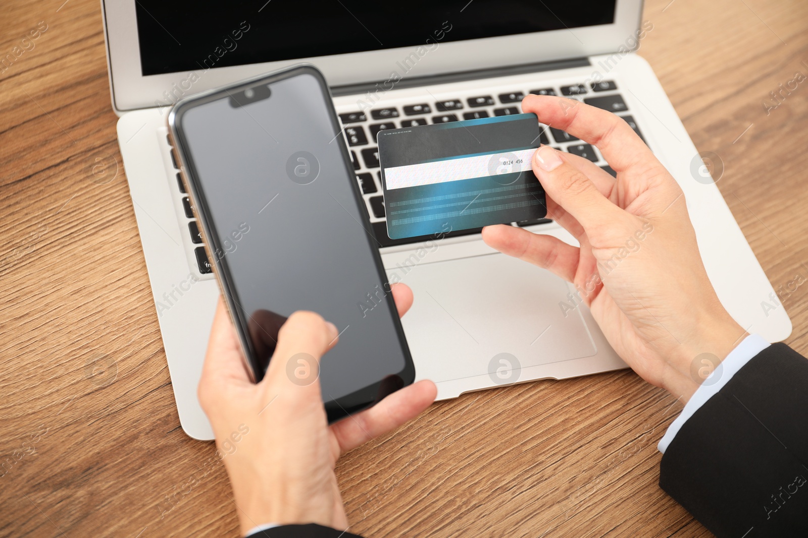 Photo of Man with credit card and smartphone at wooden table, closeup