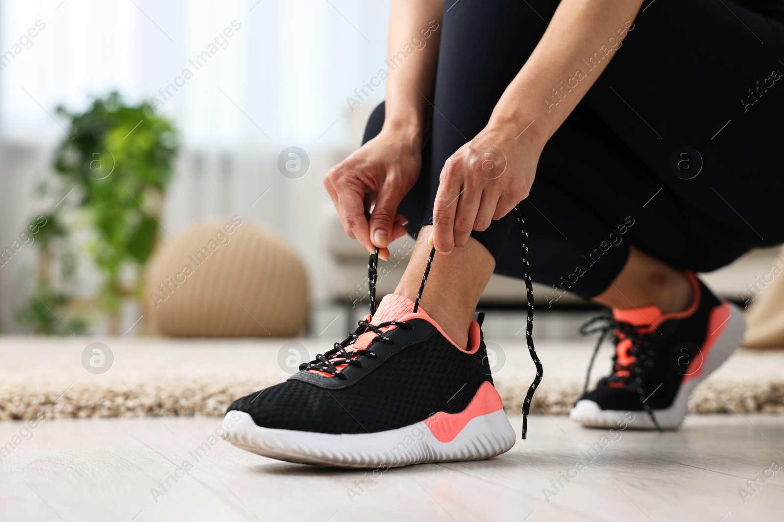 Photo of Woman tying shoelace of sneaker indoors, closeup. Space for text