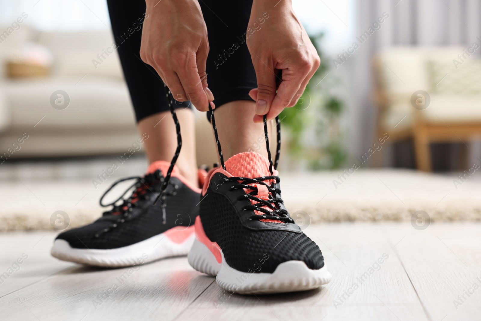 Photo of Woman tying shoelace of sneaker indoors, closeup. Space for text