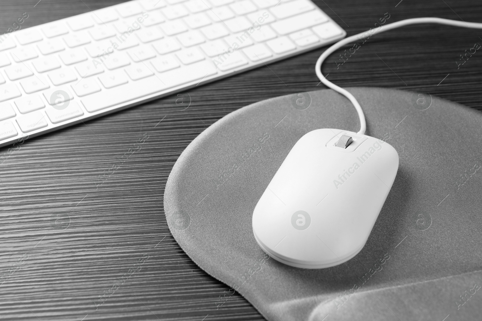 Photo of Computer mouse, mousepad and keyboard on black wooden table