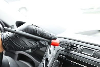 Photo of Man cleaning car interior with brush, closeup