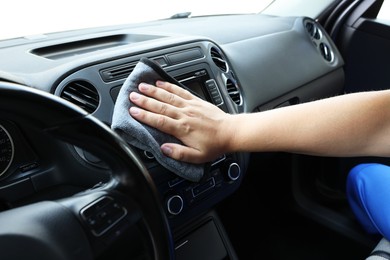 Photo of Man cleaning center console with rag, closeup