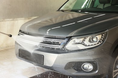 Washing auto with high pressure water jet at car wash, closeup