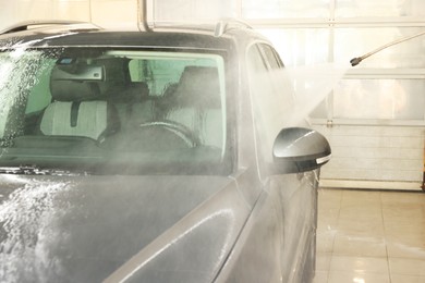 Photo of Washing auto with high pressure water jet at car wash, closeup