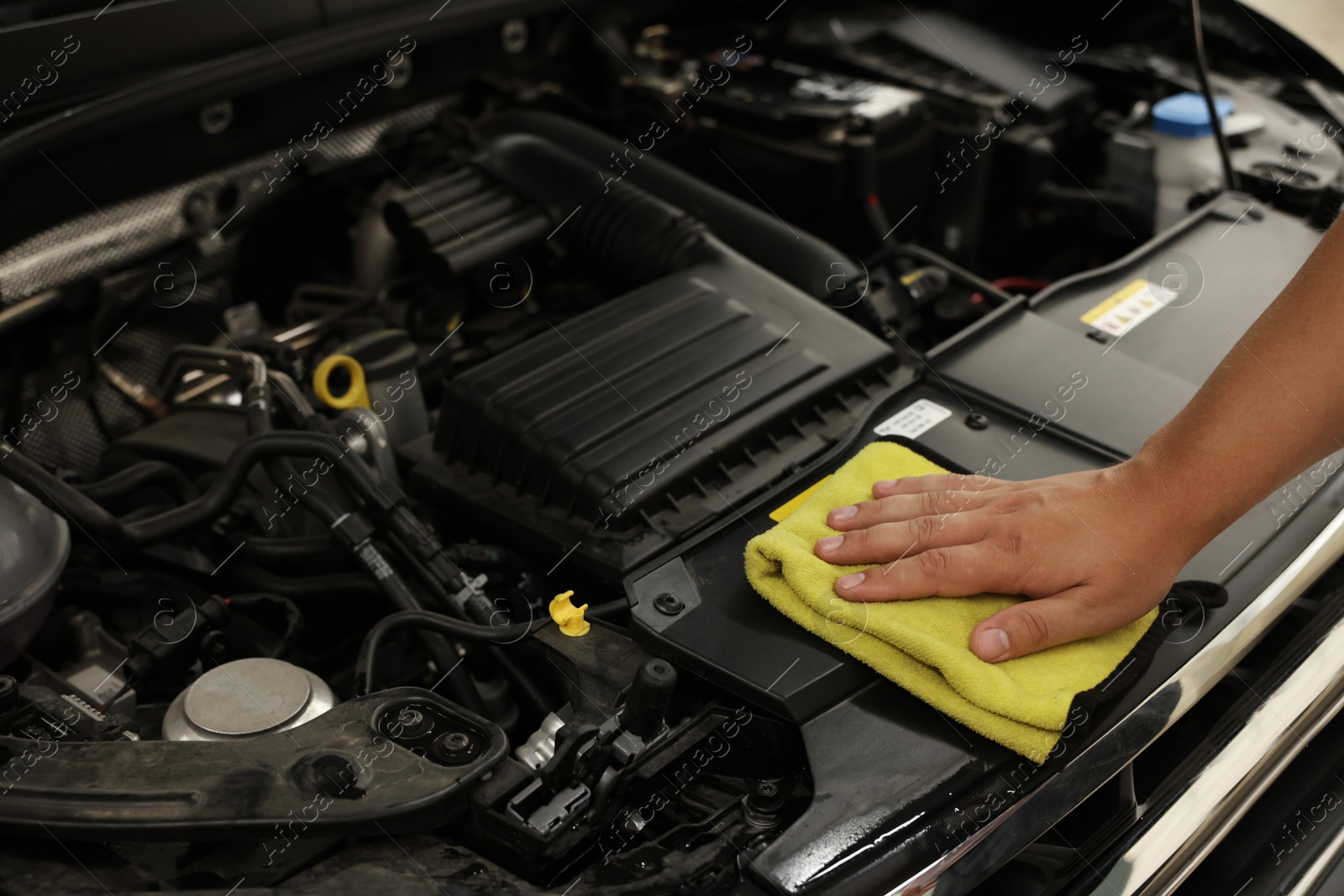 Photo of Man wiping auto engine with rag at car wash, closeup