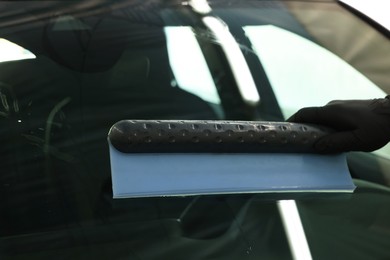 Man wiping auto with squeegee brush at car wash, closeup