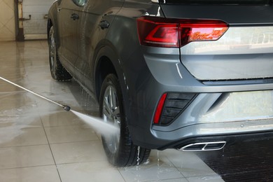 Photo of Washing auto with high pressure water jet at car wash, closeup