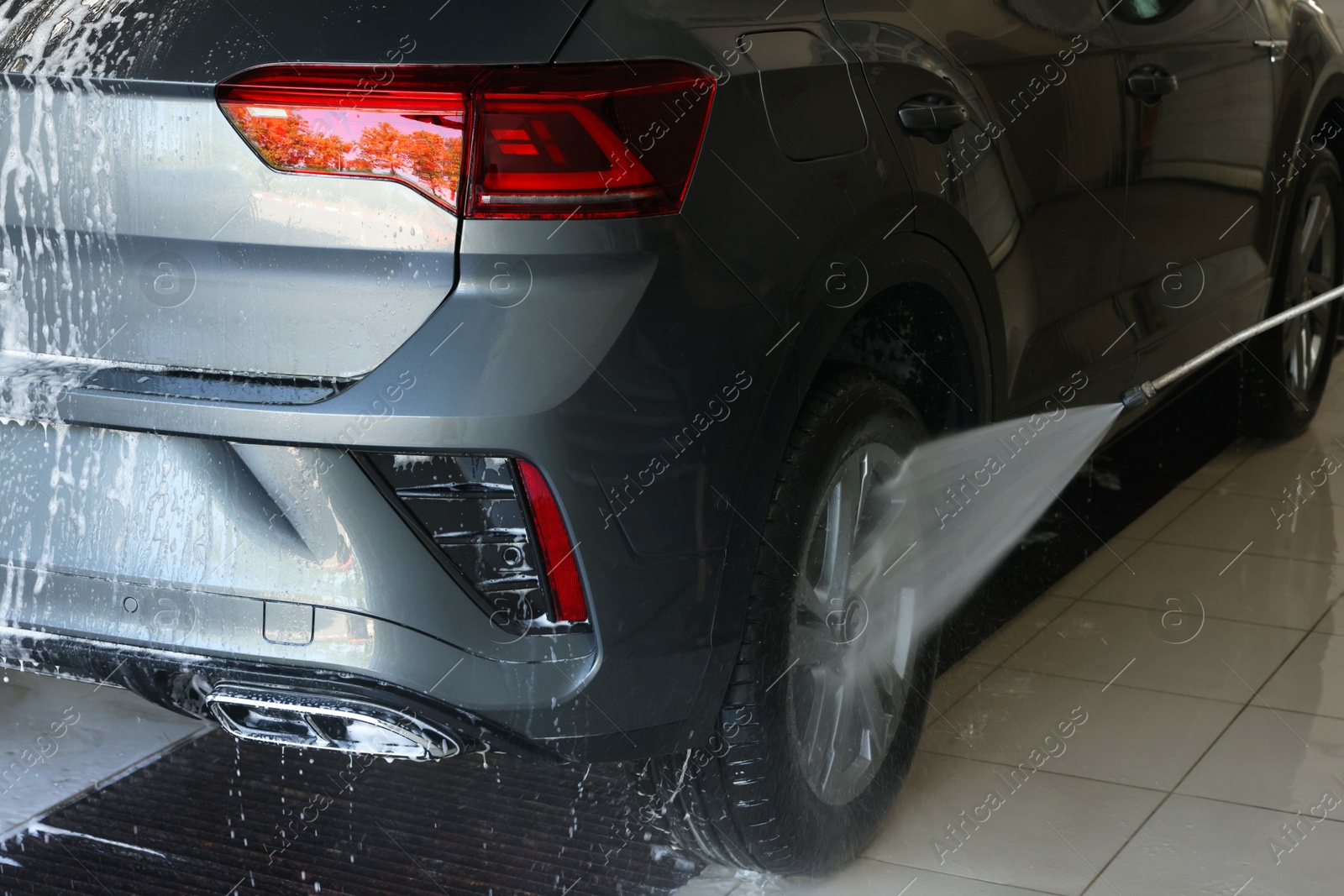 Photo of Washing auto with high pressure water jet at car wash, closeup