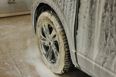 Auto covered with cleaning foam at car wash, closeup