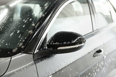 Photo of Auto covered with cleaning foam at car wash, closeup