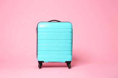 Photo of One new turquoise suitcase on pink background