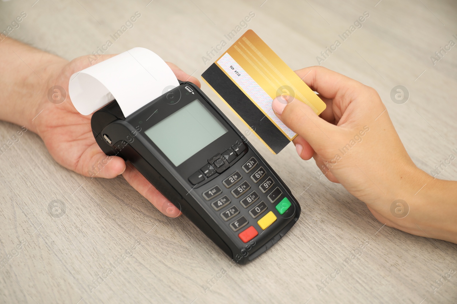 Photo of Man taking payment from client via credit card terminal at wooden table, closeup