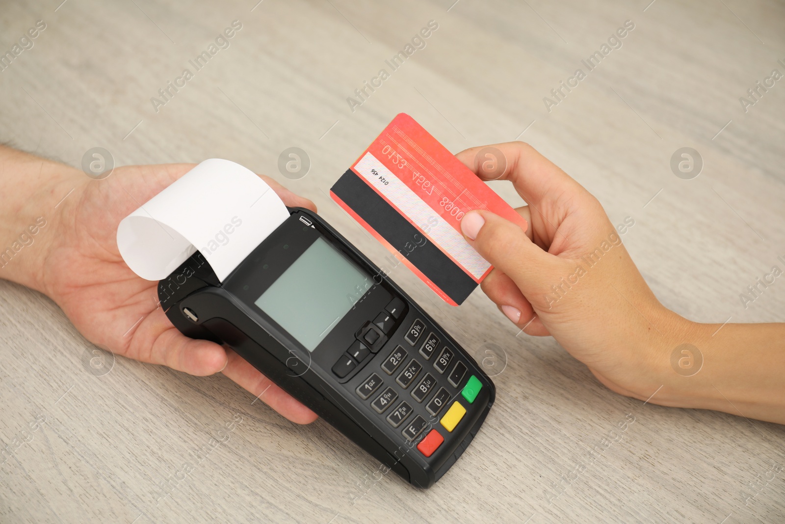 Photo of Man taking payment from client via credit card terminal at wooden table, closeup