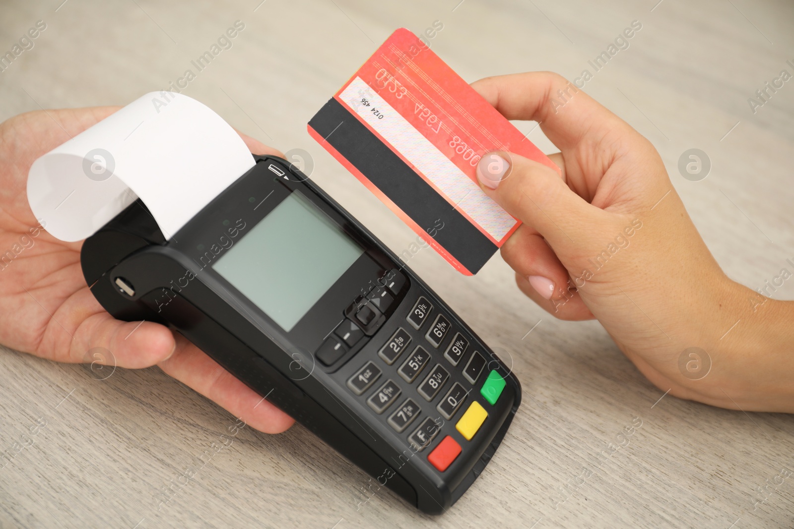 Photo of Man taking payment from client via credit card terminal at wooden table, closeup