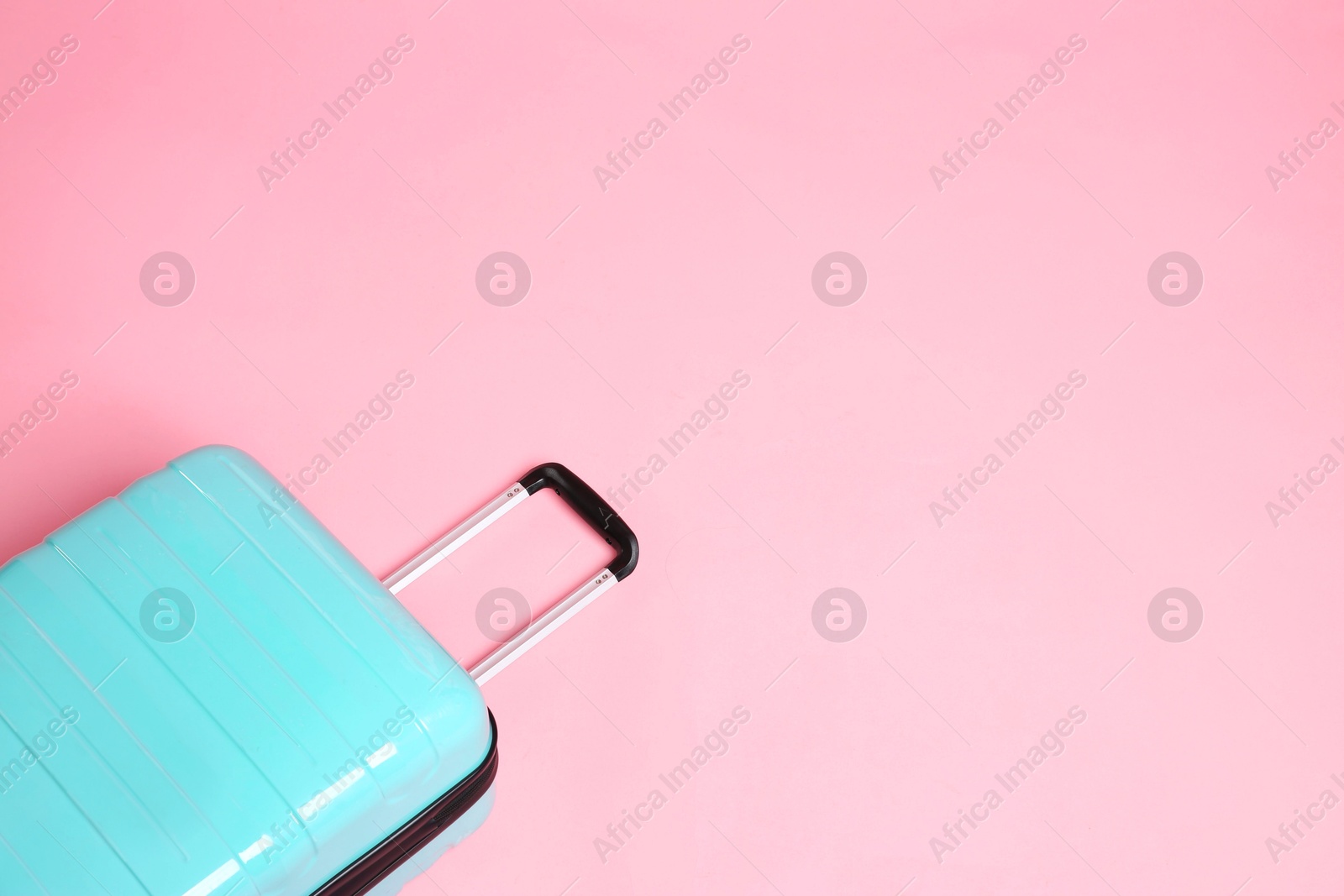 Photo of One new turquoise suitcase on pink background, above view. Space for text