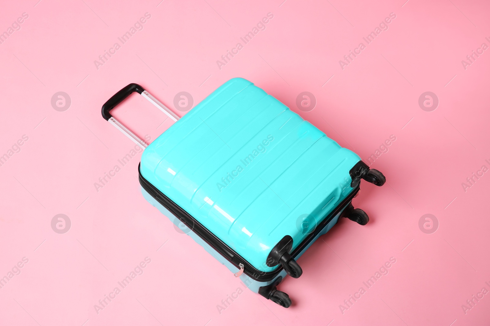 Photo of One new turquoise suitcase on pink background, above view