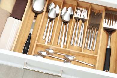 Photo of Box with cutlery in drawer, above view. Kitchen utensils storage