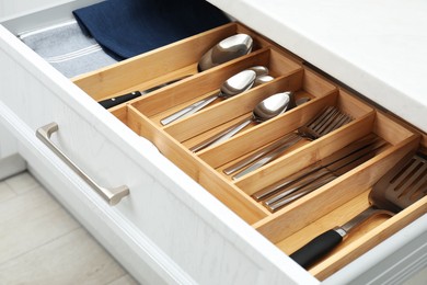 Photo of Box with cutlery in drawer, closeup. Kitchen utensils storage