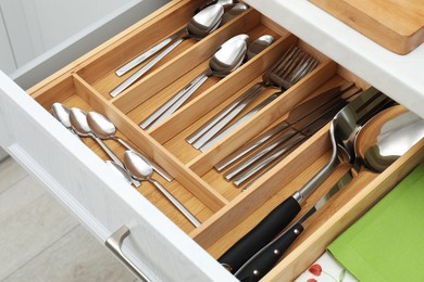 Photo of Box with cutlery in drawer, closeup. Kitchen utensils storage