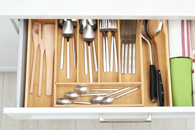 Photo of Box with cutlery in drawer, above view. Kitchen utensils storage